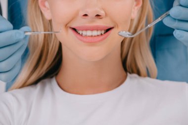 bir dişçi holding ağız ayna ve gülümseyen kadın yakınındaki diş sonda kırpılmış görünümü