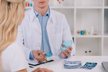 kadın ile istişare sırasında diş diş telleri antrenör sunan ortodontist görünümünü kırpılmış