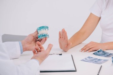 Randevu ve ret teklif etmek-in çene modeli üzerinde beyaz izole tutan ortodontist sırasında el ile eller kadının kırpılmış görünümü