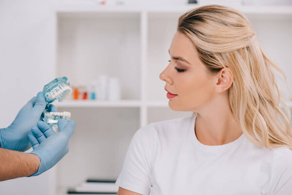 woman looking at orthodontist holding jaw model during consultation in clinic