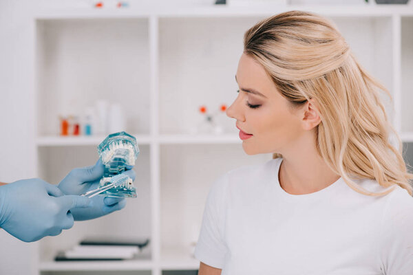 woman looking at orthodontist holding jaw model during consultation in clinic