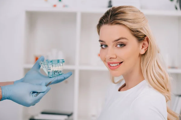 Mooie Lachende Vrouw Kijken Camera Terwijl Orthodontist Kaak Model Houden — Stockfoto