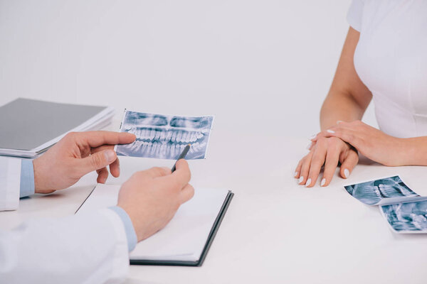 обрезанный взгляд женщины во время консультации с ортодонтом изолирован на белом
