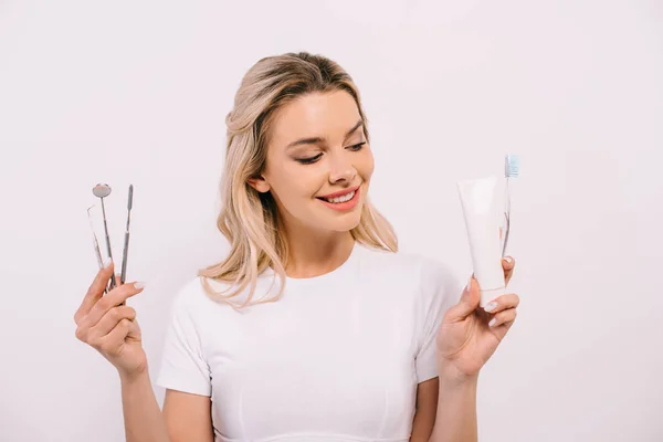 美丽的微笑的女人拿着牙膏 牙刷和牙科仪器隔离在白色 — 图库照片