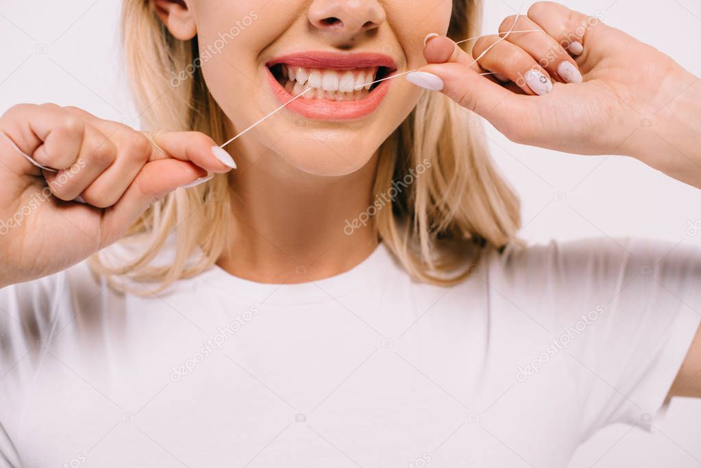 partial view of woman flossing teeth with dental floss isolated on white