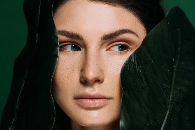 Yeşil izole yaprakları ile poz yüzündeki çiller ile genç kadın