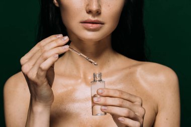 kırpılmış yeşil izole serum ile şişe tutan çıplak kadın görünümünü