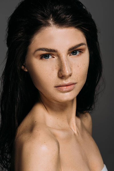 Portrait of beautiful naked woman with freckles on face isolated on grey