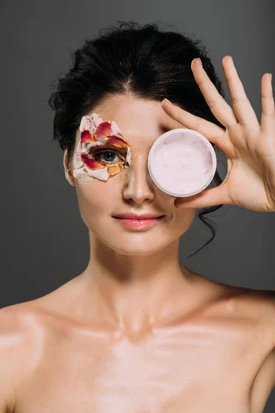 Mooie Vrouw Met Bloemblaadjes Gezicht Houden Kunststoffles Met Cosmetische Crème — Stockfoto