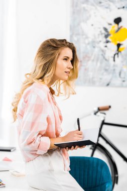 Çekici genç kadın yazma not defterinde Kareli gömlekli yan görünüm