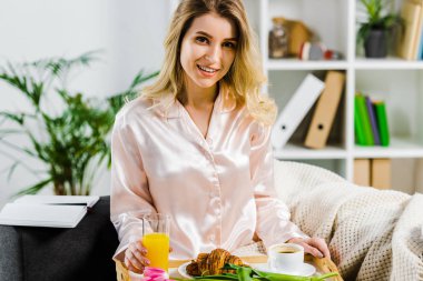 Saten pijama kahvaltı tepsisiyle tutan çekici sarışın kadın