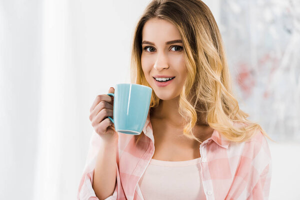 Blissful beautiful woman looking at camera and drinking coffee