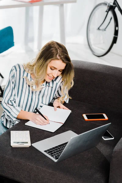 Wanita Tersenyum Dengan Laptop Dan Smartphone Menulis Notebook — Stok Foto