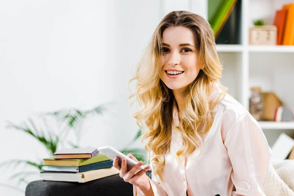 Mujer Rubia Riendo Pijama Sosteniendo Teléfono Inteligente Mirando Cámara — Foto de Stock