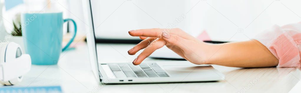 Cropped view of woman typing on laptop keyboard at workplace