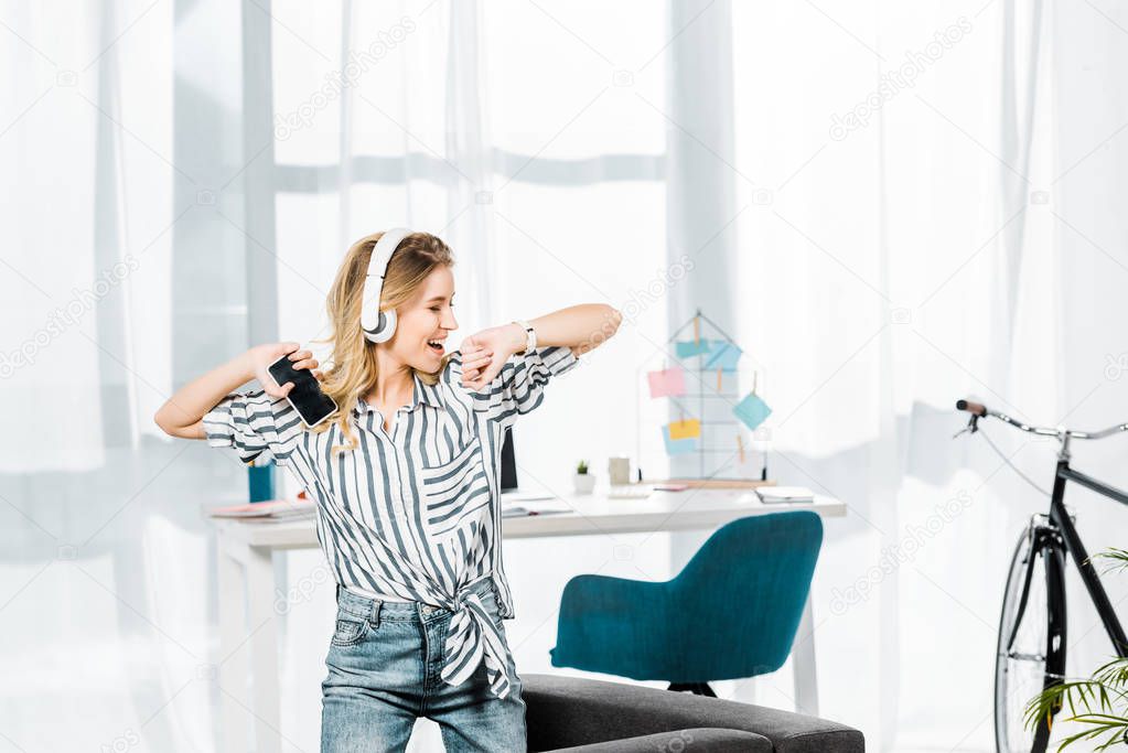 Carefree girl in striped shirt dancing and listening music in headphones