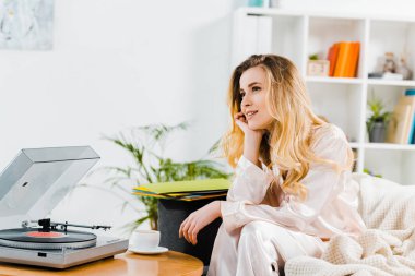 Rüya gibi genç kadın kanepede oturan ve müzik dinleme pijama