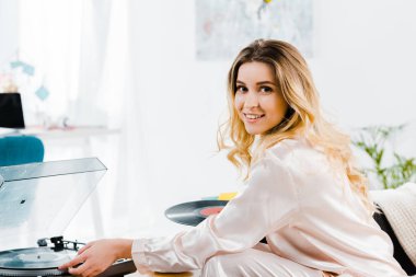 Pijama ile vinil kayıtlar gramofon kullanarak çarpıcı sarışın kadın