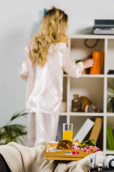 本棚の近くに立ってパジャマで金髪女性の背面図 — ストック写真