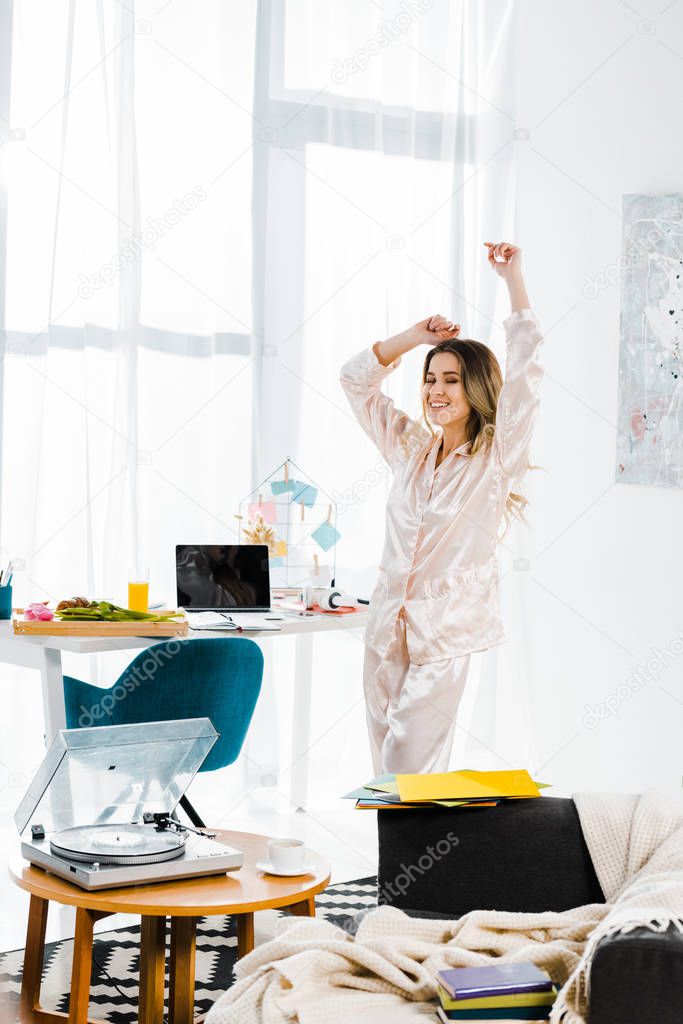 Refined young woman in pyjamas dancing in morning at home