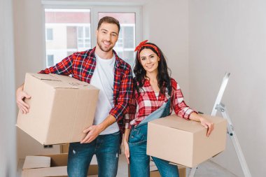 handsome boyfriend and attractive girlfriend holding boxes at home clipart