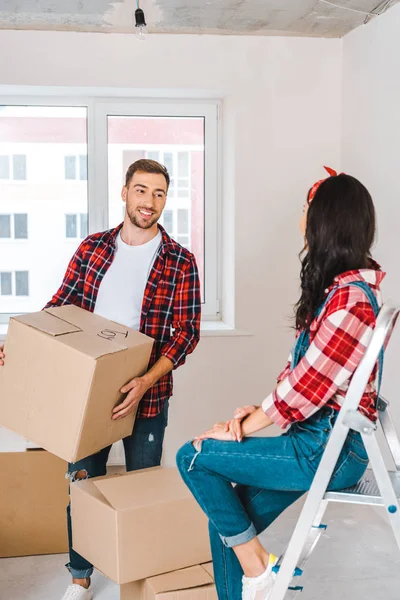 Happy Man Holding Box Looking Girlfriend Sitting Ladder — Stock Photo, Image