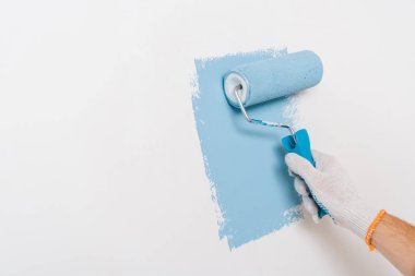 cropped view of man painting wall in blue color at home clipart