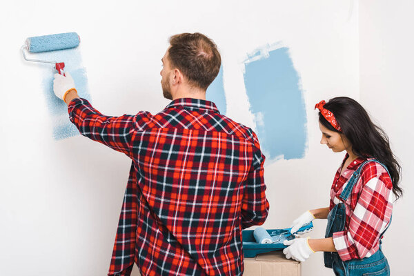 man and woman painting wall in blue color at home