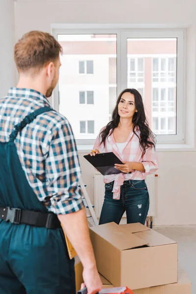 Attraktive Frau Mit Klemmbrett Und Blick Auf Handwerker — Stockfoto