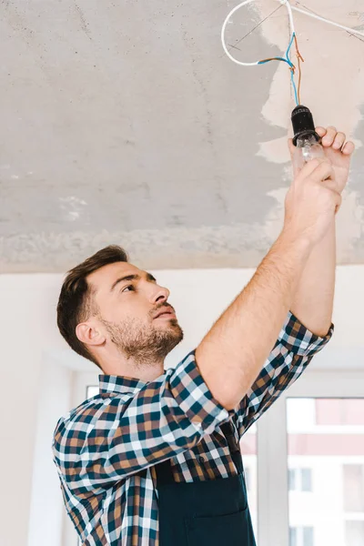 Schöner Handwerker Schaut Auf Glühbirne Aus Glas — Stockfoto