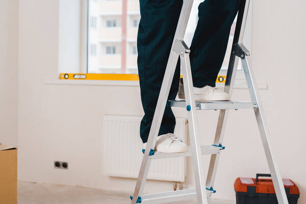 cropped view of man standing on ladder in room