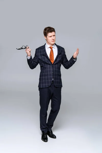 Stylish Businessman Trendy Suit Holding Eyeglasses Showing Shrug Gesture Isolated — Stock Photo, Image