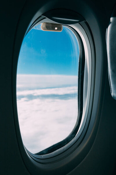 airplane window with view of blue cloudy sky