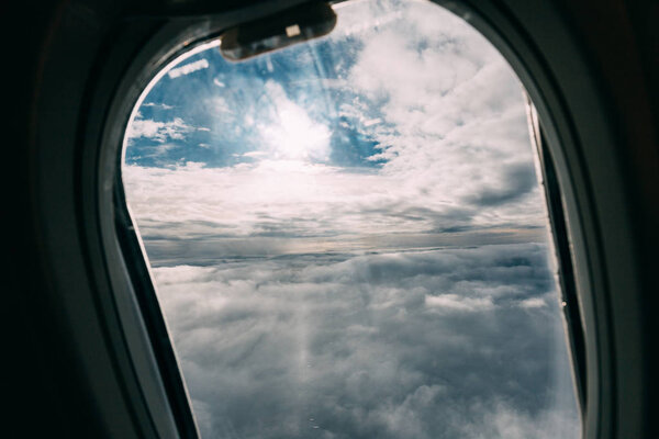 airplane porthole with beautiful cloudy sky view