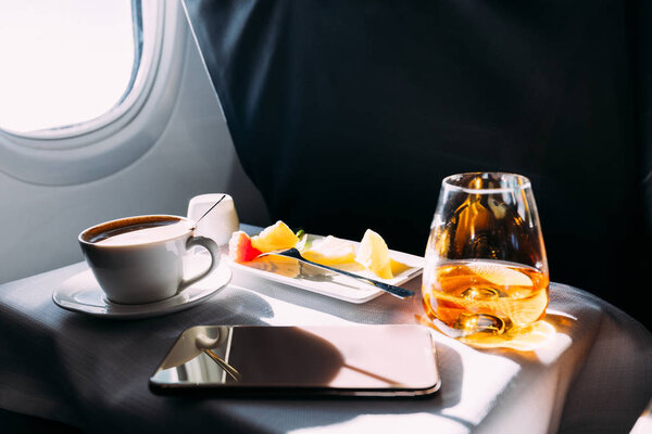 passenger table in airplane with drinks, snacks and digital tablet