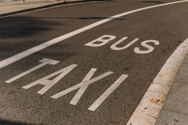 asphalt roadway with white markings, "bus" and "taxi" inscriptions, barcelona, spain