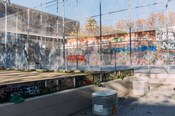 BARCELONA, SPAIN - DECEMBER 28, 2018:playground with high metallic net fence, and graffiti on wall 