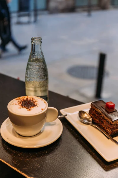 coffee cup, bottle of mineral water and saucer with cake on bar counter, barcelona, spain