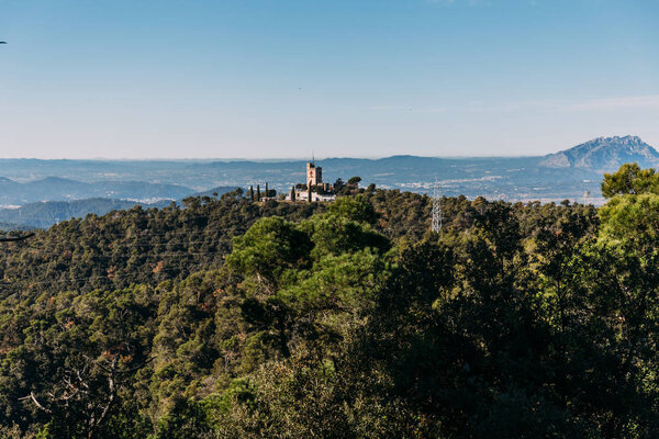 scenic view of castle and hills covered with green trees, barcelona, spain