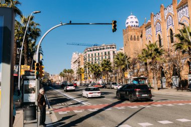 BARCELONA, SPAIN - DECEMBER 28, 2018: busy street with old multicolored building and cars moving on wide road clipart