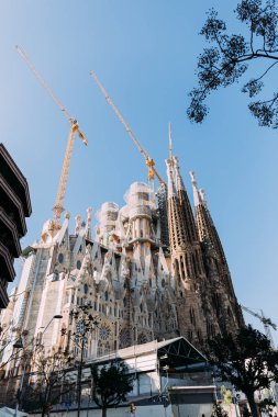BARCELONA, SPAIN - DECEMBER 28, 2018: selective focus of Temple Expiatori de la Sagrada Familia, one of the most famous buildings of Barcelona, built by Antoni Gaudi, on blue sky background clipart