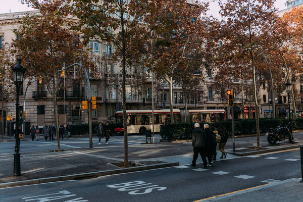 BARCELONA, SPAIN - DECEMBER 28, 2018: busy street with people crossing road and boulevard with trees