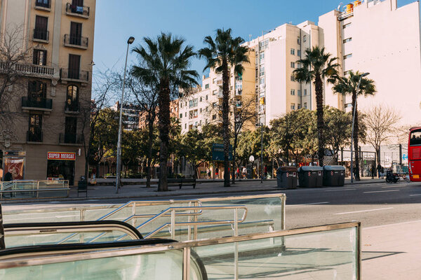 BARCELONA, SPAIN - DECEMBER 28, 2018: wide street with multistory building and tall green palm trees