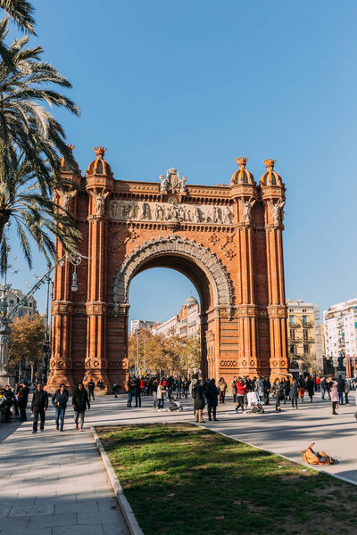 BARCELONA, SPAIN - DECEMBER 28, 2018: Arc de Triomf, famous city landmark, and people walking along wide alley