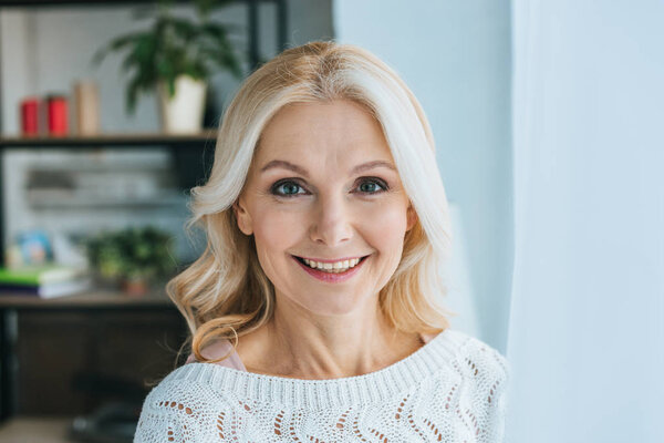 happy woman with blonde hair smiling at home