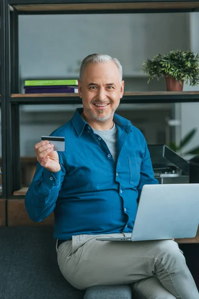 Pria Bahagia Tersenyum Sambil Memegang Kartu Kredit Dekat Laptop Rumah — Stok Foto