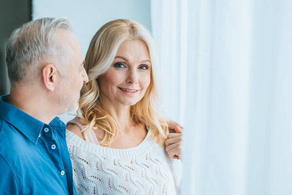 счастливый мужчина обнимает веселую жену дома