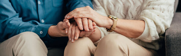 cropped view of couple holding hands at home
