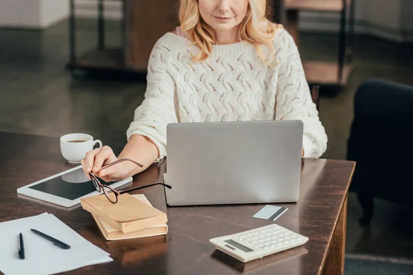 Vista Ritagliata Donna Che Tiene Gli Occhiali Seduto Vicino Gadget — Foto Stock