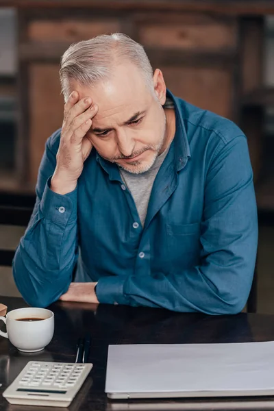 Zmęczony Człowiek Trzyma Głowę Patrząc Kubek Kawą — Zdjęcie stockowe